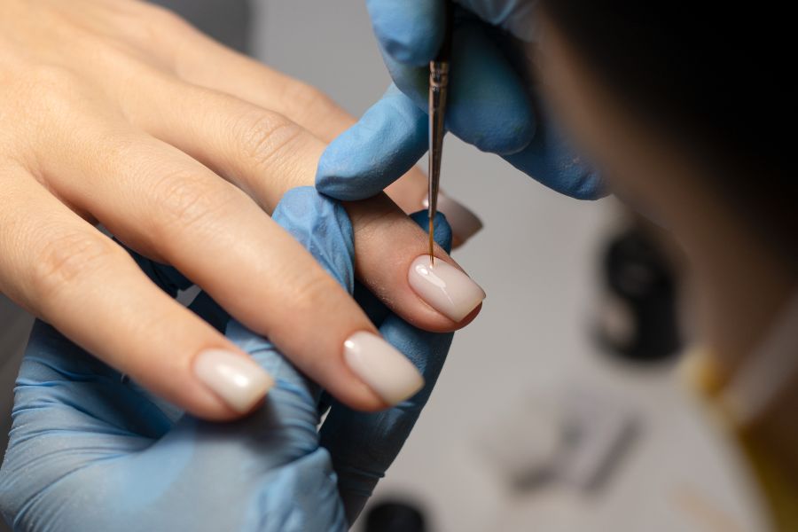 Nail artist applying polish to a client’s square-shaped nails during a professional manicure.